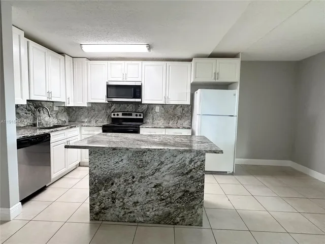 a kitchen with granite countertop a stove a sink and a refrigerator