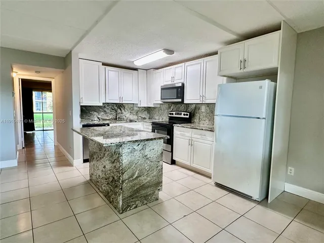 a kitchen with stainless steel appliances granite countertop a refrigerator sink and cabinets