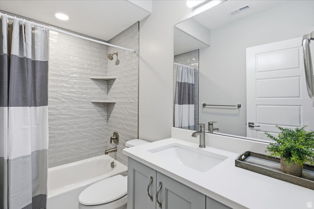 21 Pier Place Tooele, UT 84074 - Photo 77 of 112 Full bathroom featuring a white porcelain tub, textured white subway tile surround with two built-in corner shelves, a white solid surface vanity countertop with integrated sink, and gray cabinetry with brushed nickel hardware