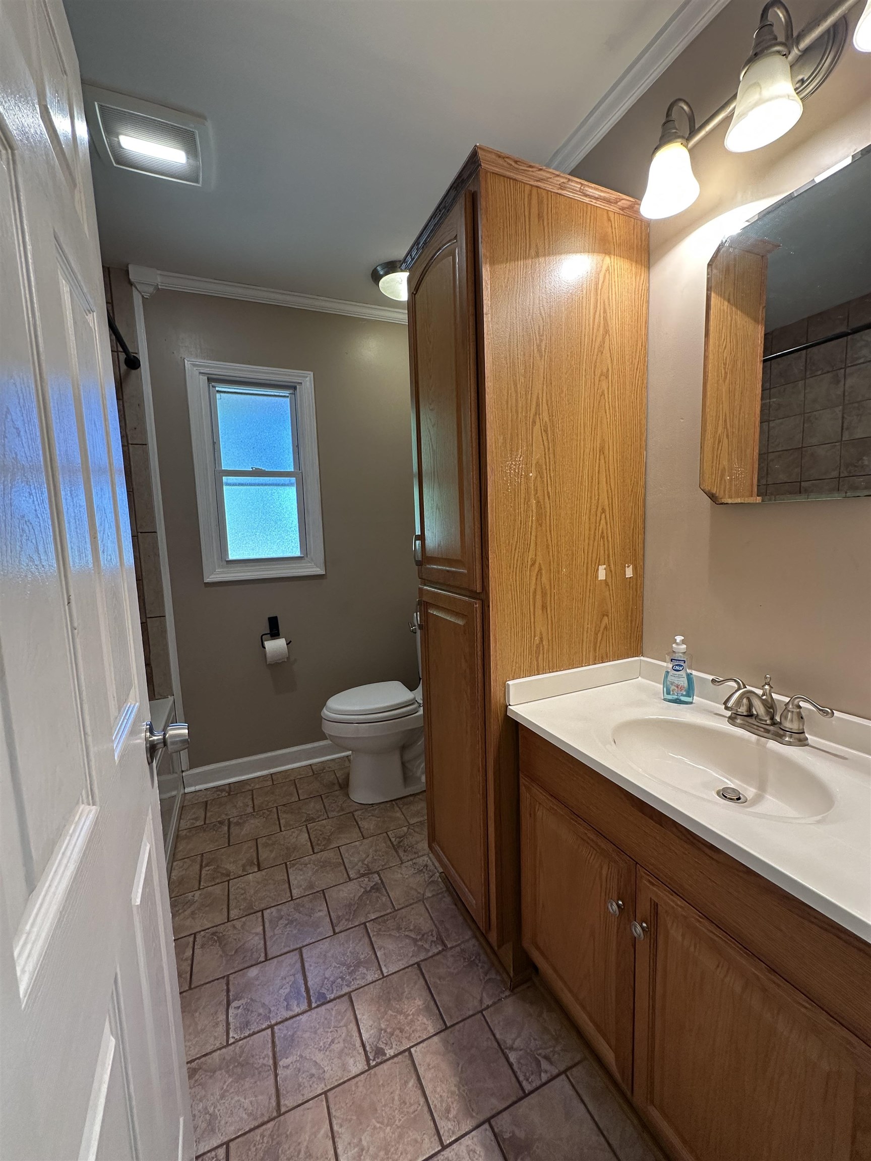 7874 Shamrock Road Millington, TN 38053 - Photo 11 of 17 Bathroom featuring a vanity with an integrated sink, wood-finish cabinetry, a tall storage cabinet, tiled flooring, and a window for natural light