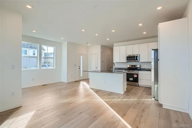 a kitchen with stainless steel appliances kitchen island granite countertop a stove a sink and a refrigerator with wooden floor