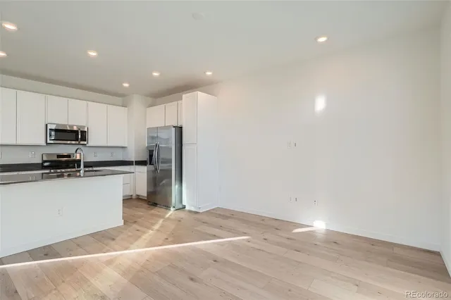 a kitchen with granite countertop a refrigerator stove top oven and sink