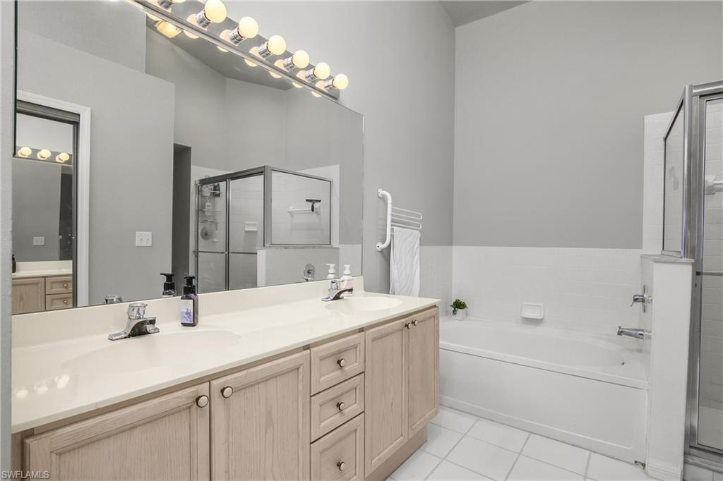 13061 Hamilton Harbour Drive, Unit R1 Naples, FL 34110 - Photo 22 of 23 Full bathroom with double vanity, a garden tub, light tile patterned floors, and a shower stall