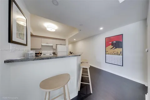 a living room with stainless steel appliances furniture a large window and a kitchen view