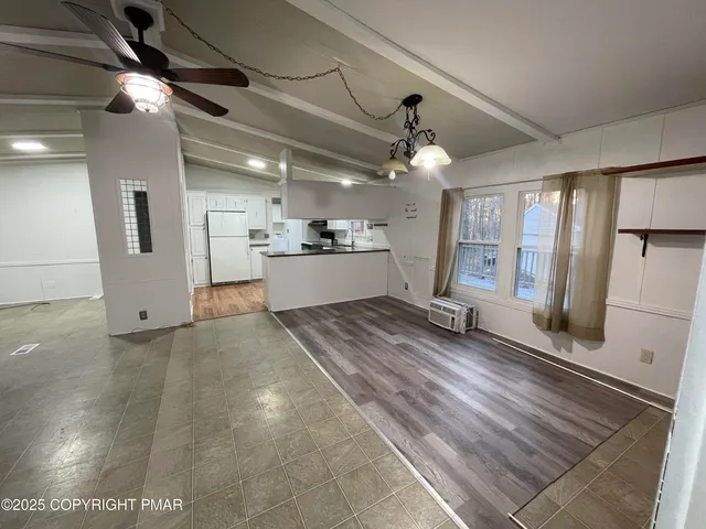 a view of an empty room with a window and a kitchen