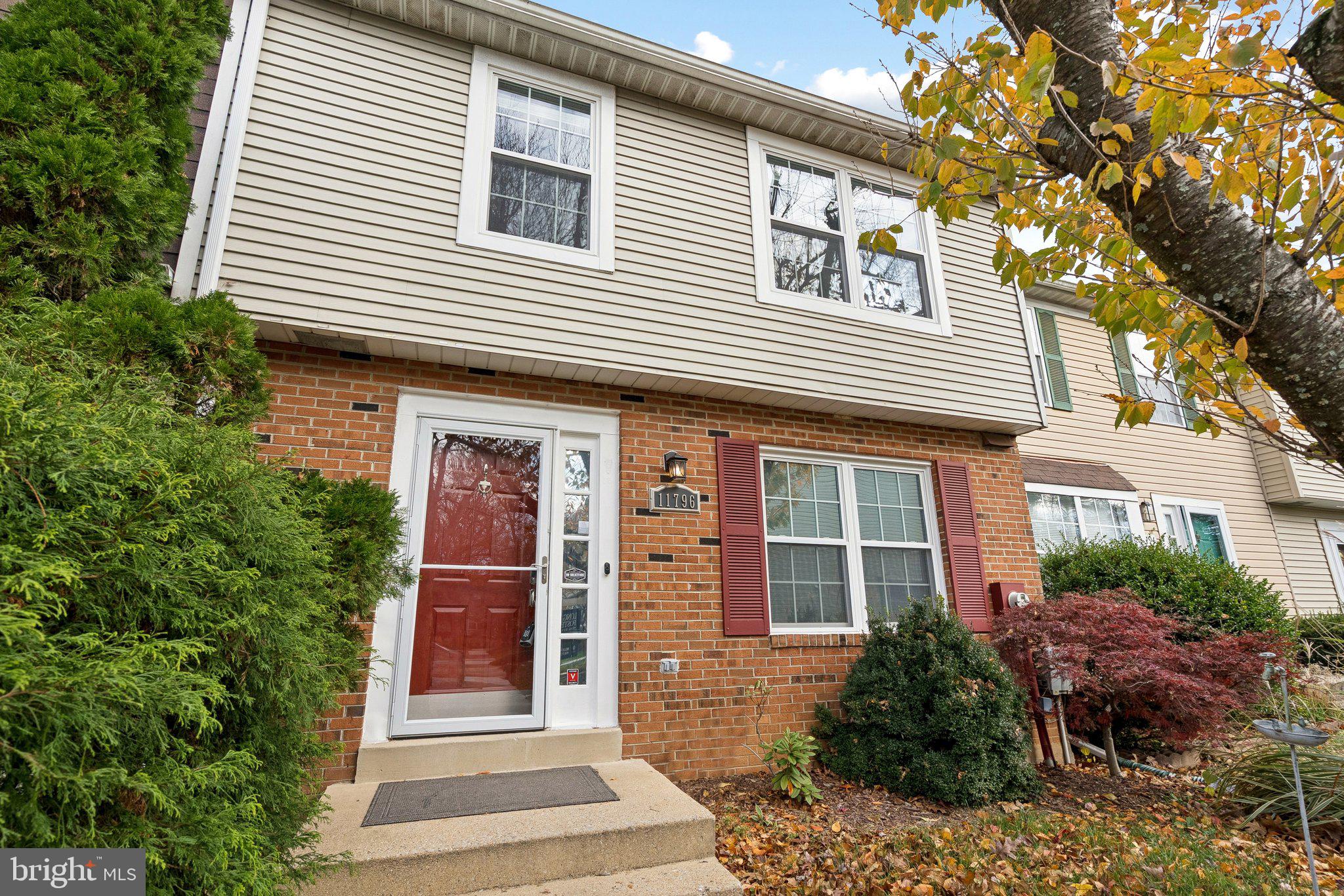 a front view of a house with glass windows and plants