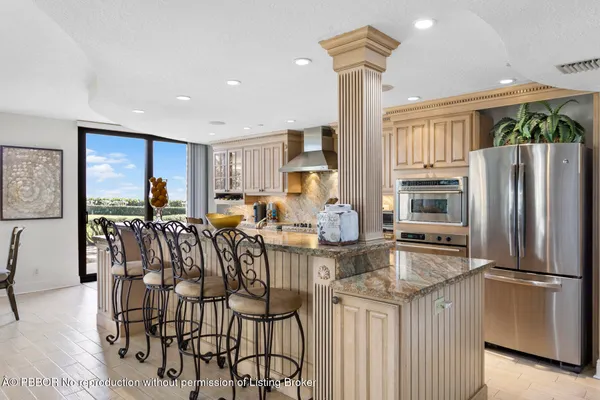 a kitchen with stainless steel appliances kitchen island granite countertop a refrigerator a stove a microwave oven a dining table and chairs with wooden floor