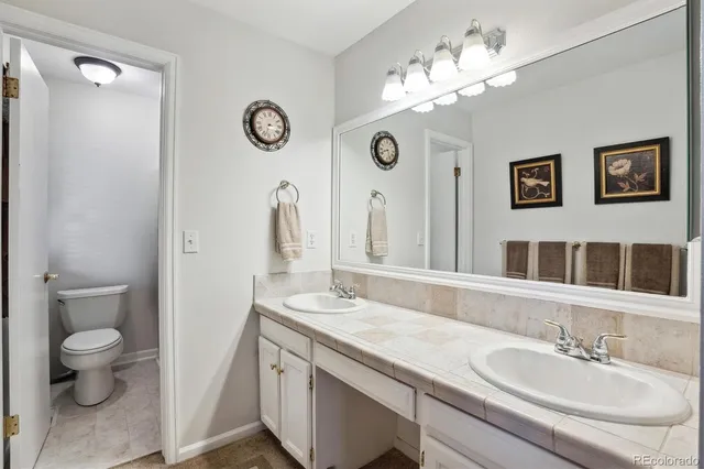 a bathroom with a granite countertop sink a toilet and a mirror