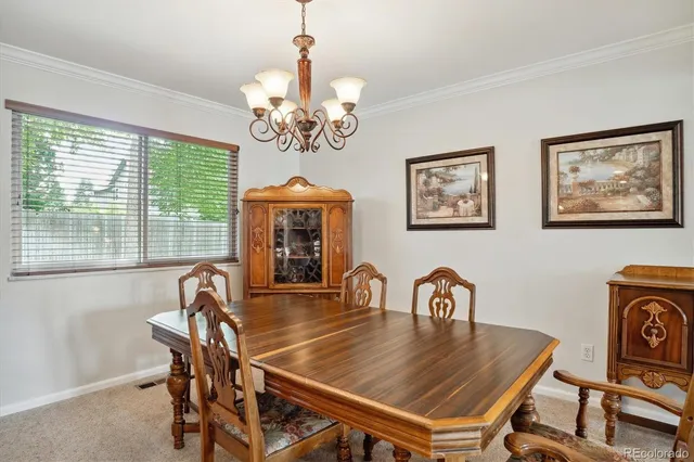 a view of a dining room with furniture a chandelier and a window