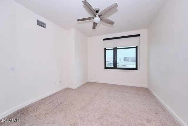 an empty room with a window and a ceiling fan