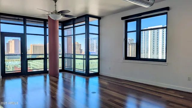 a view of empty room with wooden floor and fan
