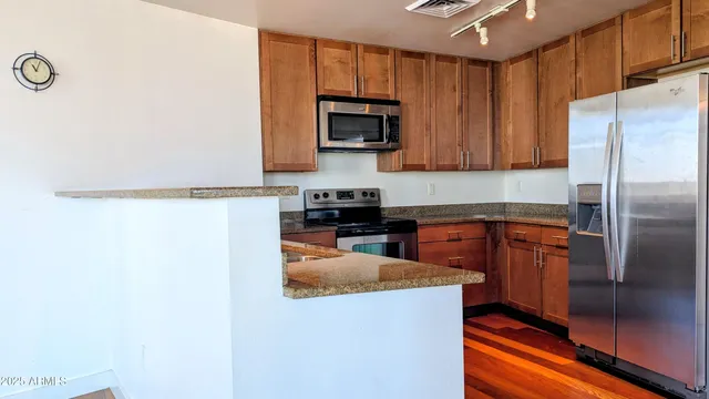 a kitchen with stainless steel appliances granite countertop a refrigerator a stove top oven a sink and dishwasher