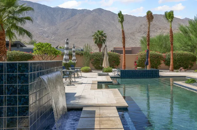 a view of a swimming pool with a lounge chair and palm trees
