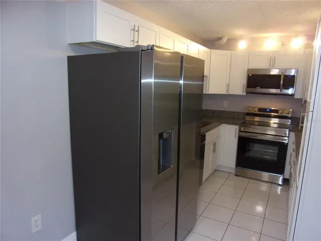 a kitchen with stainless steel appliances granite countertop a refrigerator and a stove top oven