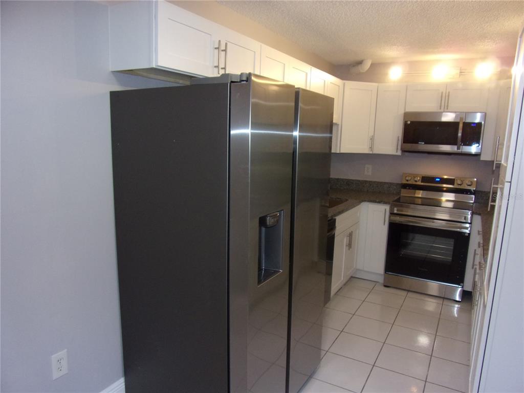 1345 Pine Ridge Circle East, Unit C2 Tarpon Springs, FL 34688 - Photo 3 of 22 a kitchen with stainless steel appliances granite countertop a refrigerator and a stove top oven