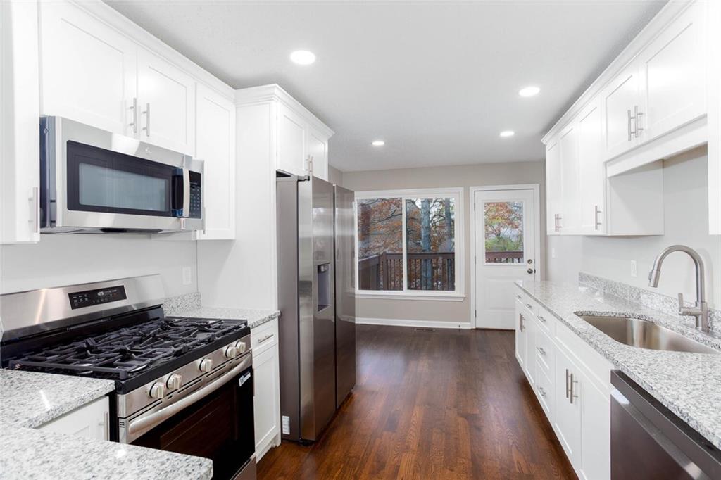 3162 Hadrian Court Powder Springs, GA 30127 - Photo 15 of 49 a kitchen with stainless steel appliances a sink dishwasher a refrigerator a stove top oven a wooden floor and a large window with wooden floor