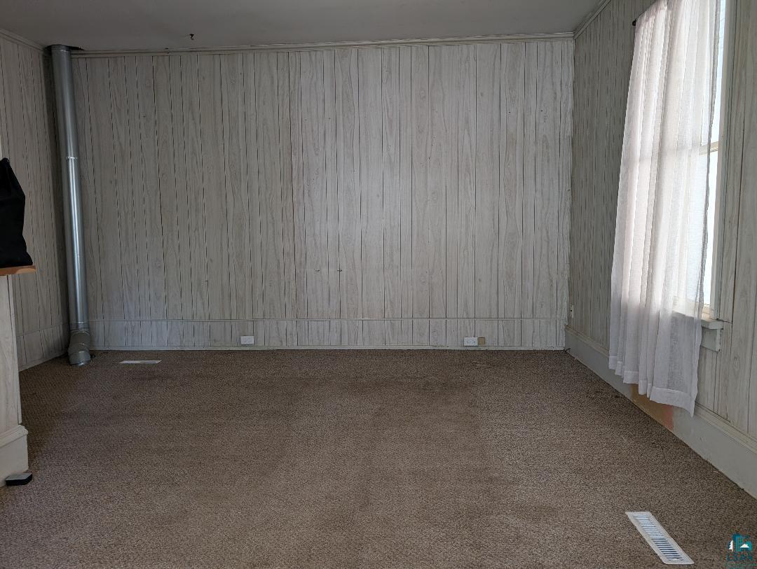 513 South Main Street Mellen, WI 54546 - Photo 11 of 22 Room featuring wood-look paneled walls, neutral carpet flooring, and a window with sheer curtains