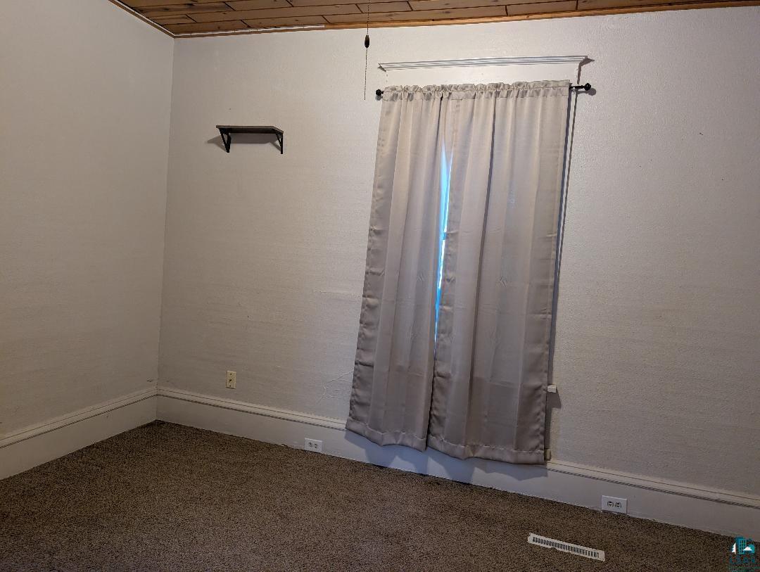 513 South Main Street Mellen, WI 54546 - Photo 13 of 22 Interior room featuring a wood-panel ceiling, textured wall finish, and neutral-toned carpet flooring