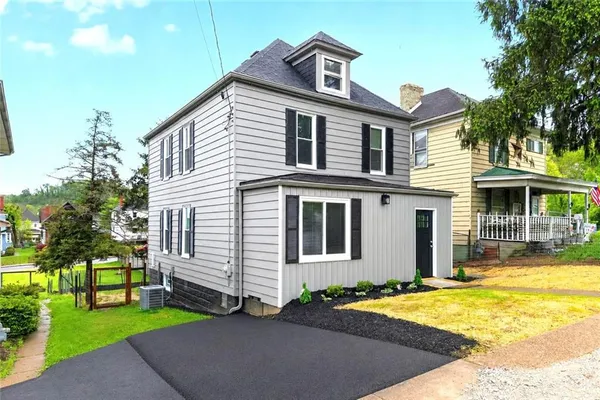 a front view of a house with a yard and trees