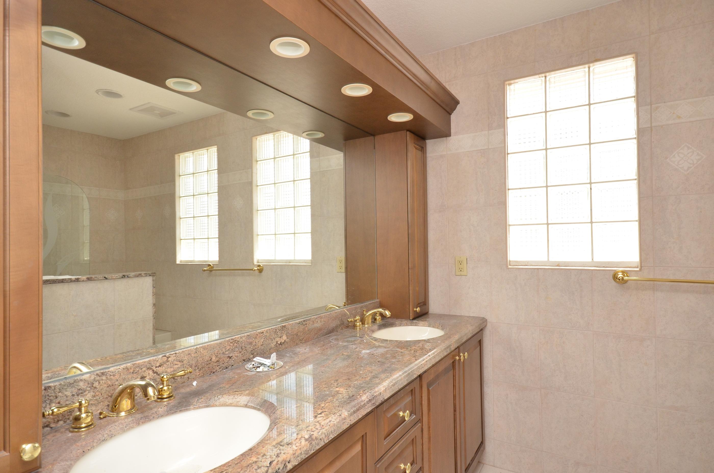 10873 Ravel Court Boca Raton, FL 33498 - Photo 15 of 18 a bathroom with a granite countertop sink a large mirror a and a bathtub