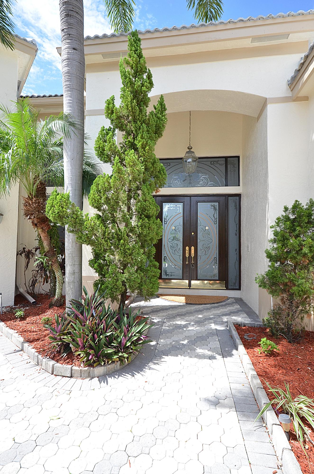 10873 Ravel Court Boca Raton, FL 33498 - Photo 3 of 18 a view of a house with potted plants and a large tree