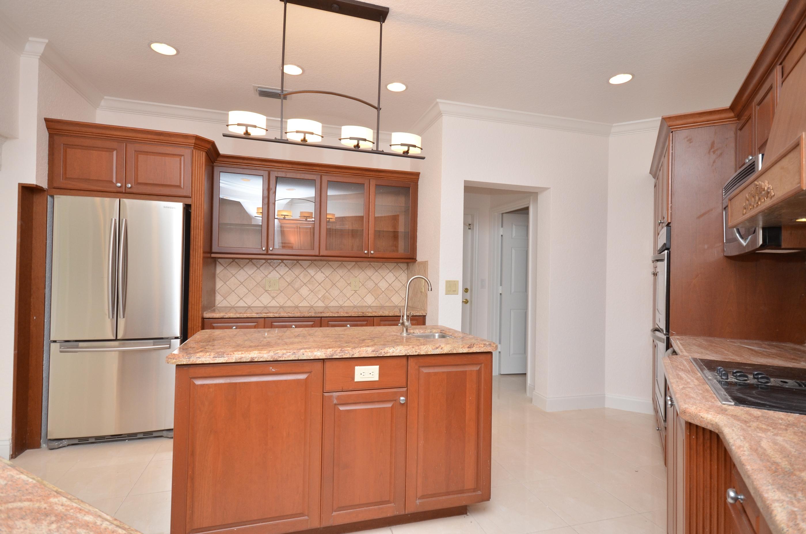 10873 Ravel Court Boca Raton, FL 33498 - Photo 7 of 18 a kitchen with stainless steel appliances granite countertop a refrigerator a stove and a sink with wooden floor