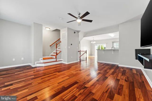 a view of empty room with wooden floor and fan