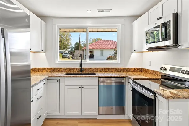 a kitchen with stainless steel appliances granite countertop a sink and a stove