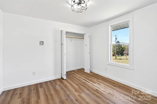 a view of a bedroom with wooden floor and a window