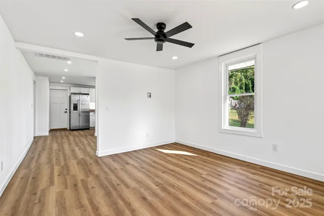 a view of empty room with wooden floor and ceiling fan
