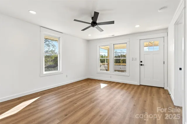 a view of an empty room with wooden floor and a window
