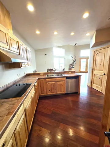 a kitchen with stainless steel appliances granite countertop wooden cabinets a sink a stove a refrigerator with wooden floors