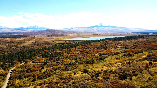 a view of a living room and kitchen with furniture and a floor to ceiling window