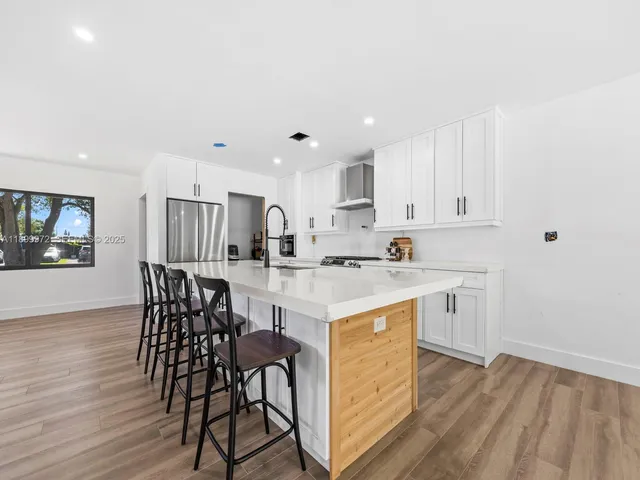 a kitchen with stainless steel appliances kitchen island granite countertop a table chairs sink and cabinets