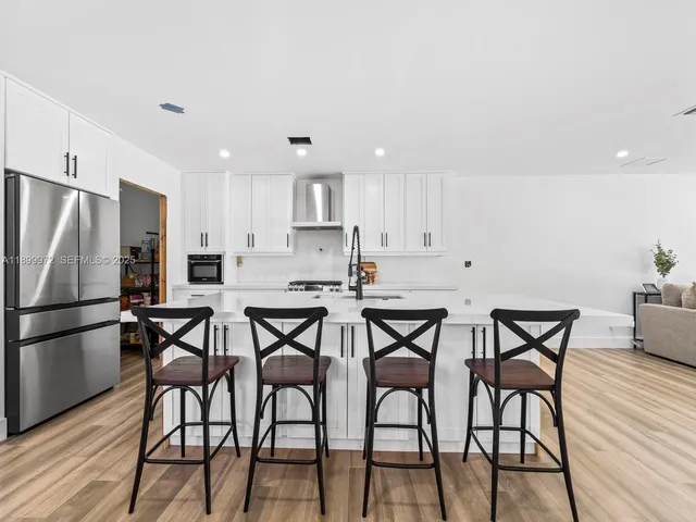 a kitchen with stainless steel appliances a table chairs refrigerator and wooden floor