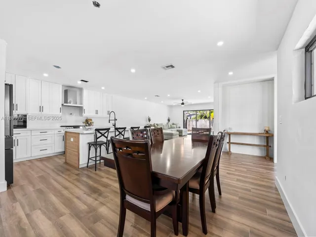 a view of a dining room and kitchen with a table chairs stove and wooden floor