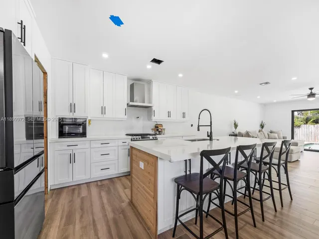 a kitchen with white cabinets stainless steel appliances and chairs