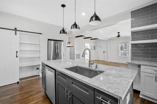 a view of a kitchen with stainless steel appliances granite countertop a sink and a wooden floor