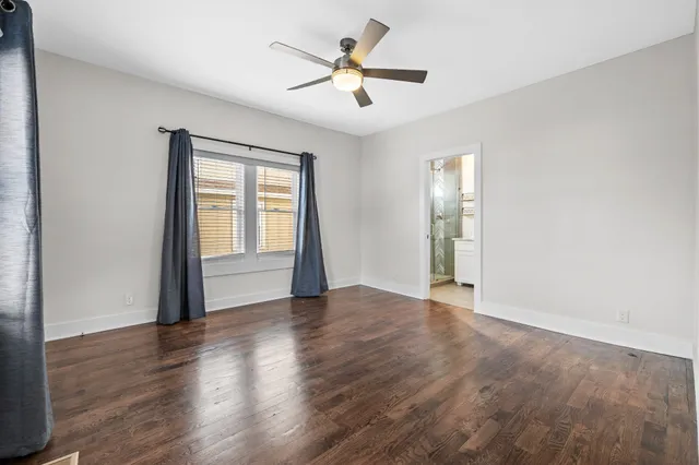 a view of a hallway with wooden floor and a bathroom