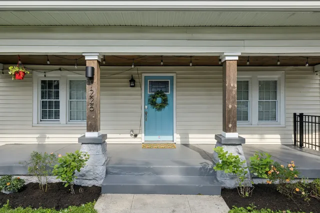 a view of a house with potted plants and a bench