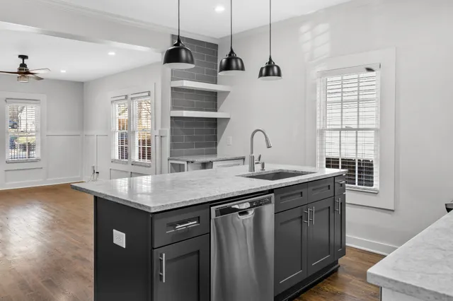 a kitchen with stainless steel appliances granite countertop a sink a window and wooden floor