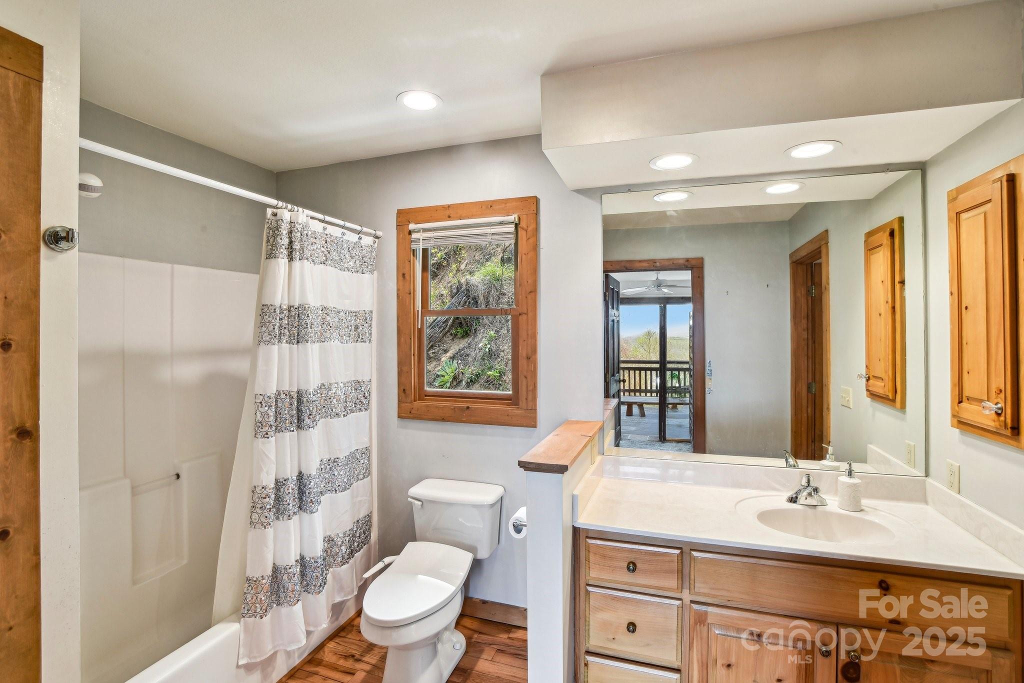 1426 Setzercove Road Maggie Valley, NC 28751 - Photo 20 of 48 a bathroom with a granite countertop sink toilet a mirror a vanity and shower