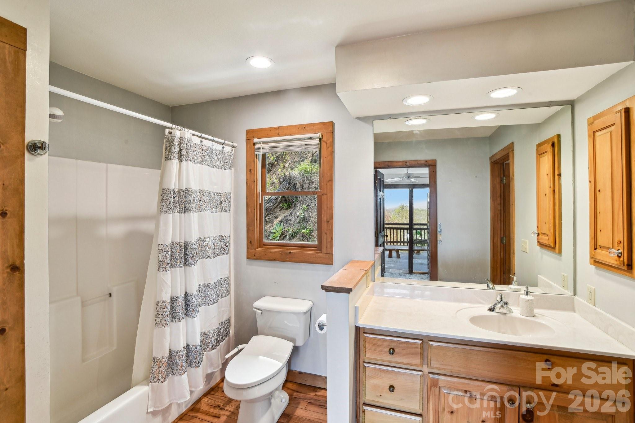 1426 Setzercove Road Maggie Valley, NC 28751 - Photo 23 of 48 a bathroom with a granite countertop sink toilet a mirror a vanity and shower