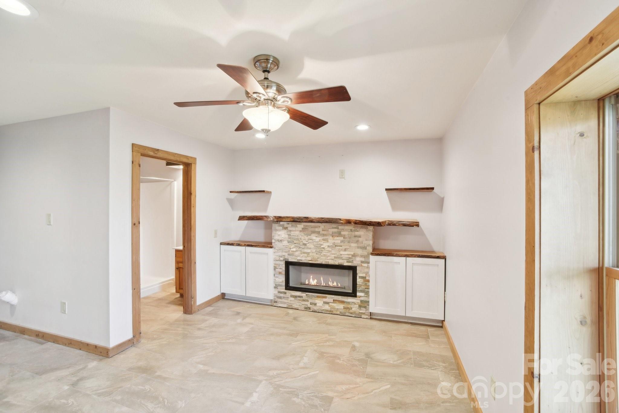 1426 Setzercove Road Maggie Valley, NC 28751 - Photo 26 of 48 an empty room with a fireplace and a ceiling fan