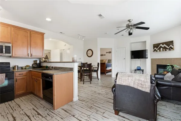 a kitchen with stainless steel appliances granite countertop a stove top oven a sink dishwasher and white cabinets with wooden floor