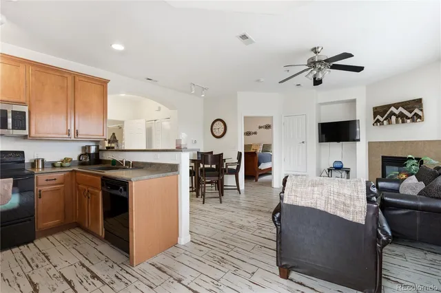 a kitchen with stainless steel appliances granite countertop a stove top oven a sink dishwasher and white cabinets with wooden floor