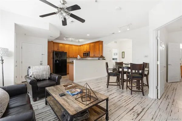 a living room with furniture kitchen view and a wooden floor