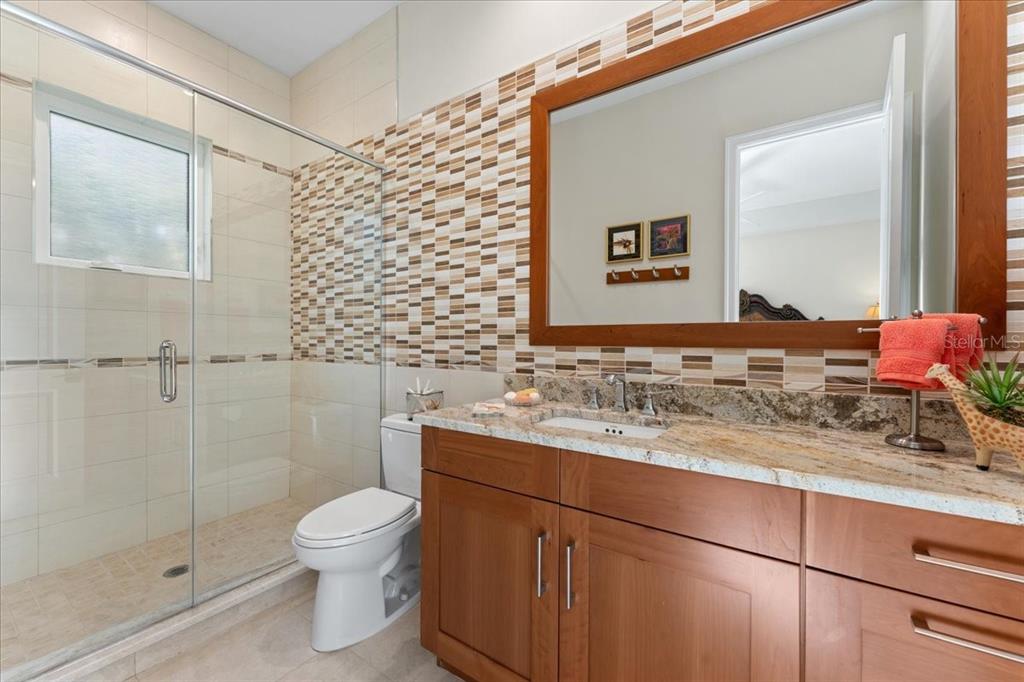 2708 North Beach Road, Unit 2 Englewood, FL 34223 - Photo 42 of 65 a bathroom with a granite countertop sink toilet and shower