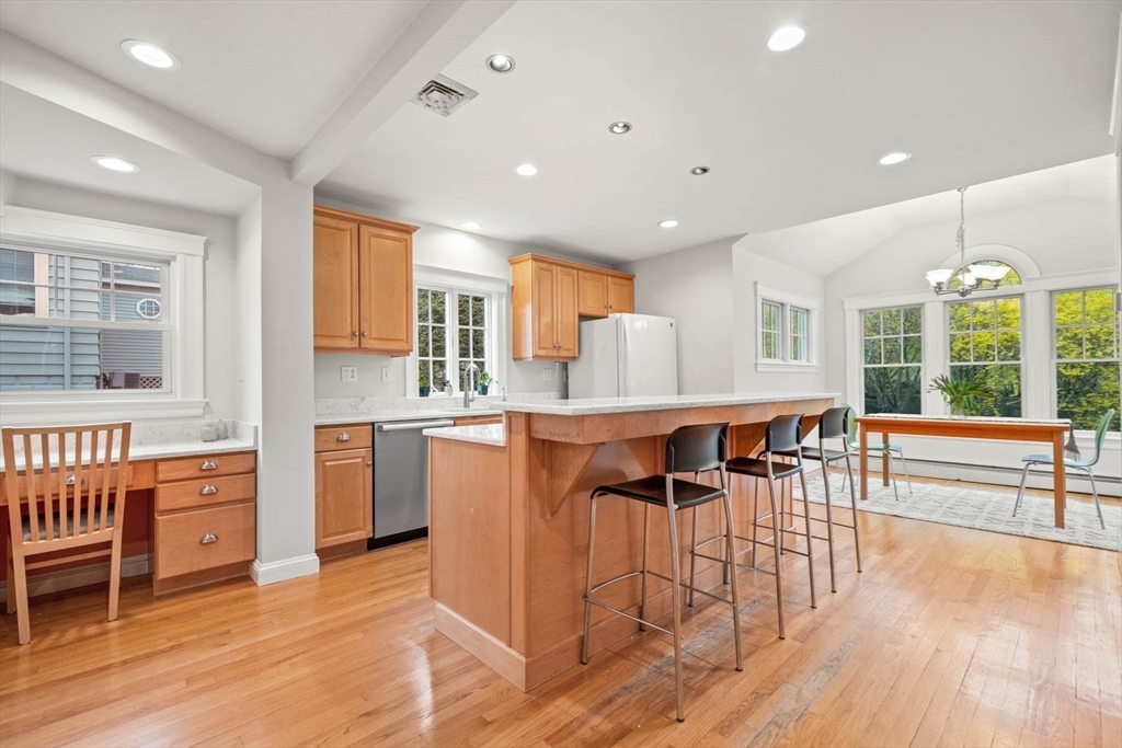 50 Allen Road Winchester, MA 01890 - Photo 12 of 29 a kitchen with stainless steel appliances kitchen island granite countertop a stove a refrigerator a sink a dining table and chairs with wooden floor