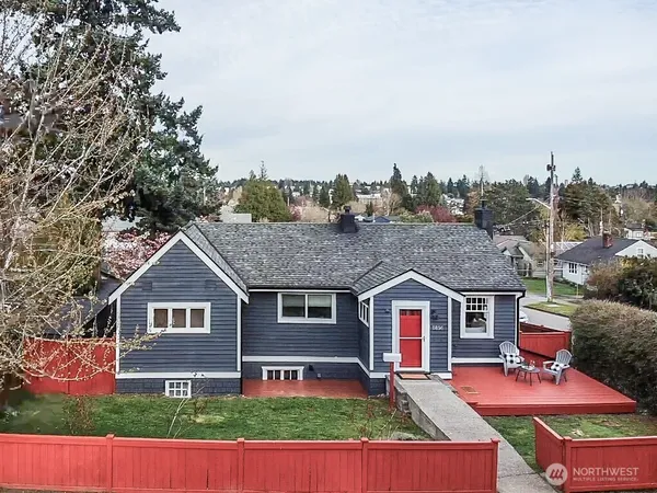 an aerial view of residential houses with yard and trees in the background